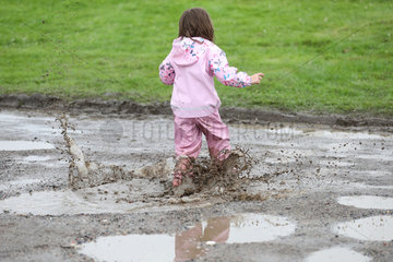 Hamburg  Kind in Regenkleidung rennt durch eine Pfuetze