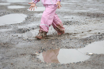 Hamburg  Detailaufnahme  Kind in Regenkleidung rennt durch eine Pfuetze