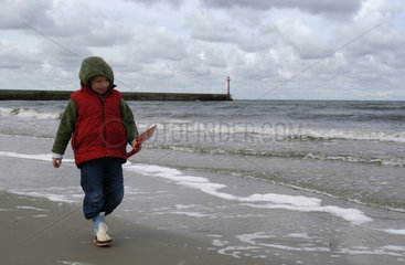 Ein kleiner Junge laeuft am Strand entlang