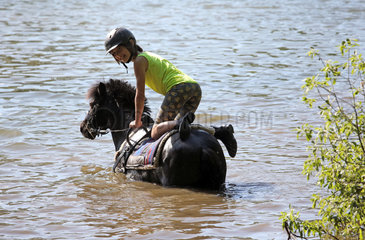Oberoderwitz  Maedchen turnt auf ihrem Pony in einem See