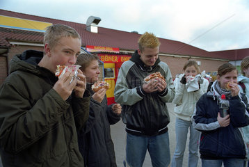 Jugendliche essen Doener vor einem Supermarkt