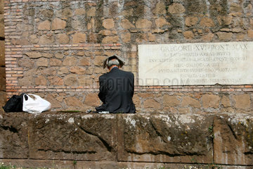 sitzende Mann vor die Alte Mauer von Rom