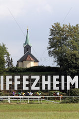 Iffezheim  Pferde und Jockeys im Rennen vor dem Iffezheim-Schriftzug unter der Kapelle