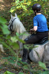 Zernikow  Frau reitet auf ihrem Pferd im Schritt durch einen Wald
