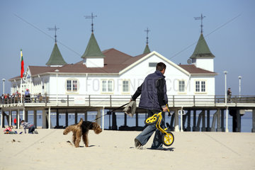 Ahlbeck  Tourist mit Hund vor der Seebruecke am Strand an der Ostsee