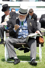 Epsom  Grossbritannien  Mann mit Zylinder schaut auf sein Handy