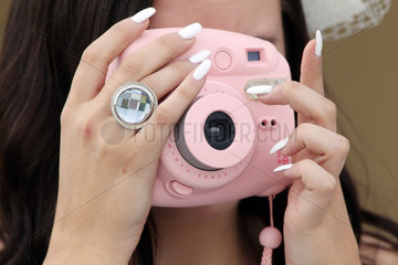 Iffezheim  Deutschland  Detailaufnahme  Frau macht ein Foto mit einer rosafarbenen Kompaktkamera