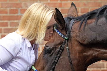 Hoppegarten  Frau kuesst ihr Pferd auf die Stirn