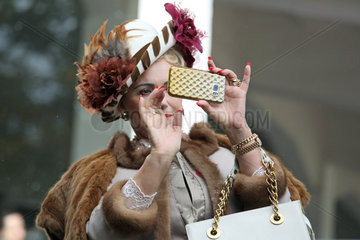 Hoppegarten  Deutschland  elegant gekleidete Frau macht ein Foto mit ihrem Smartphone