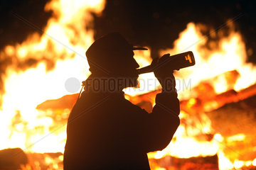 Wandlitz  Mann mit Cowboyhut trinkt Bier vor einem Lagerfeuer
