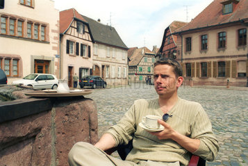 Tourist trinkt einen Cafe au lait  Bergheim im Elsass
