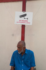 Singapur  Republik Singapur  Mann sitzt unter einem Hinweisschild