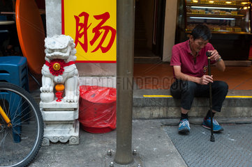 Singapur  Republik Singapur  Mann sitzt am Strassenrand