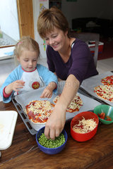 Handewitt  Deutschland  ein Maedchen bereitet eine selbst gemachte Pizza mit ihrer Mutter zu