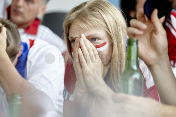 Woman holding hands over face in disappointment while watching sports match at home