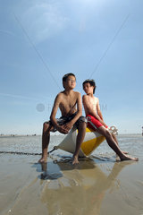 St. Peter-Ording  Deutschland  Kinder sitzen am Strand bei Niedrigwasser auf eine Positionstonne