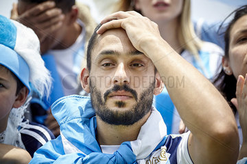 Argentinian football fan holding hand on head in disappointment at match