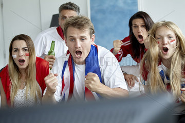 British football fans cheering while watching match on TV