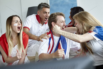 British football fans celebrating victory while watching match on TV
