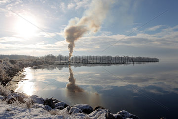 Gluecksburg  Deutschland  Rauchsaeule spiegelt sich in der Wasseroberflaeche der Flensburger Foerde