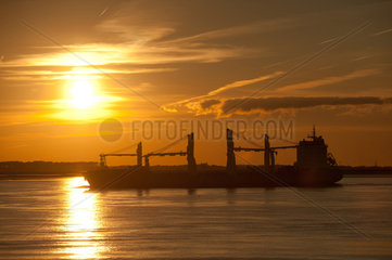 Brokdorf  Deutschland  ein Frachtschiff bei Sonnenuntergang auf der Elbe