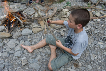 Blatti Alm  Schweiz  Junge schnitzt einen Spiess feur das Grillen am Lagerfeuer