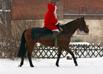 Hoppegarten  Deutschland  ein Weihnachtsmann reitet auf einem Pferd durch den Schnee