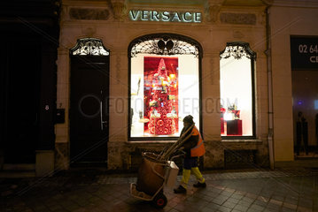 Bruessel  Region Bruessel-Hauptstadt  Belgien - Strassenkehrerin vor VERSACE-Boutique am Abend.