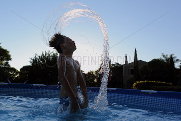 Torre Alfina  Italien  Silhouette  Junge wirft im Swimmingpool sein nasses Haar zurueck