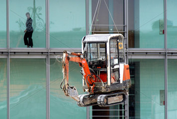 Minibagger schwebt vor Glasfassade  Berlin