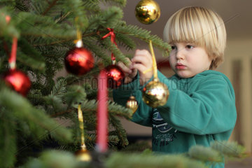 Harrislee  Deutschland  ein Junge dekoriert einen Weihnachtsbaum