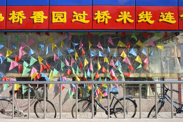 Peking  Fahrraeder vor bunt geschmuecktem Schaufenster
