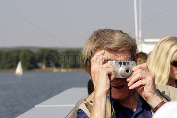 Bad Saarow  fotografierender Mann auf einem Ausflug mit einem Rundfahrtschiff auf dem Scharmuetzelsee