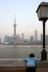 Shanghai  ein Junge liegt auf der Mauer am Bund