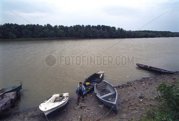 Ein Donaufischer geht an Land an der Donau  Rumaenien