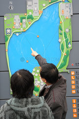 Peking  Mann zeigt auf Plan vom Beihai-Park