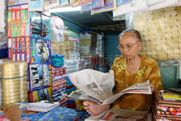 Vietnam  Verkaeuferin liest Zeitung in ihrem Geschaeft im Bin Tay-Mark
