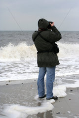 Rerik  ein Mann wird von einer Welle umspuelt waehrend er fotografiert