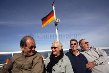 Touristen und Deutschlandfahne auf Schiff auf der Ostsee