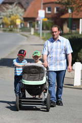 Koehn  Vater mit seinen Kindern und einem Kinderwagen unterwegs