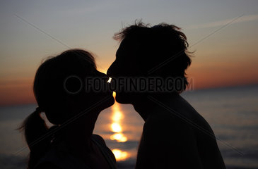Kaegsdorf  Deutschland  Silhouette  Paar kuesst sich bei Sonnenuntergang am Meer