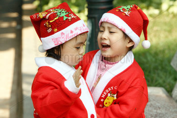 Zwei Kinder in Nikolauskostuemen in einem Park von Hanoi