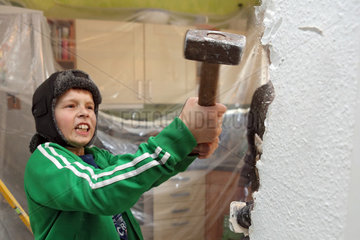 Berlin  Deutschland  Junge schlaegt mit einem Hammer auf eine Wand ein