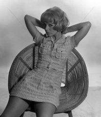 Berlin  DDR  junge Frau im Minikleid raekelt sich auf einem Baststuhl