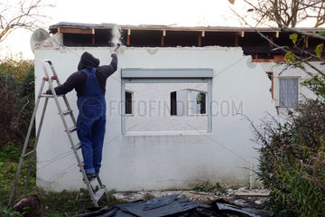 Berlin  Deutschland  Handwerker schlaegt beim Rueckbau einer Gartenlaube eine Wand ein