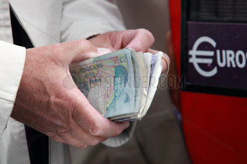 Ascot  Grossbritannien  englische Pfundnoten werden vor einem Euro-Wechselautomaten in den Haenden gehalten
