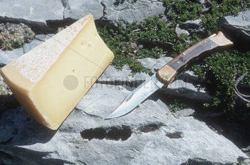 Messer und Kaese liegen auf einem Stein