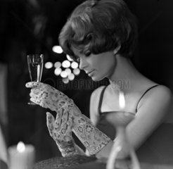 Berlin  DDR  elegant gekleidete junge Frau haelt ein Sektglas in der Hand