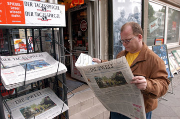 Mann liest Tageszeitung Die Welt an einem Kiosk