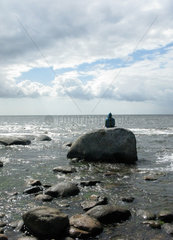 Karlskrona  Schweden  Tourist sitzt auf einem Felsen an der Kueste